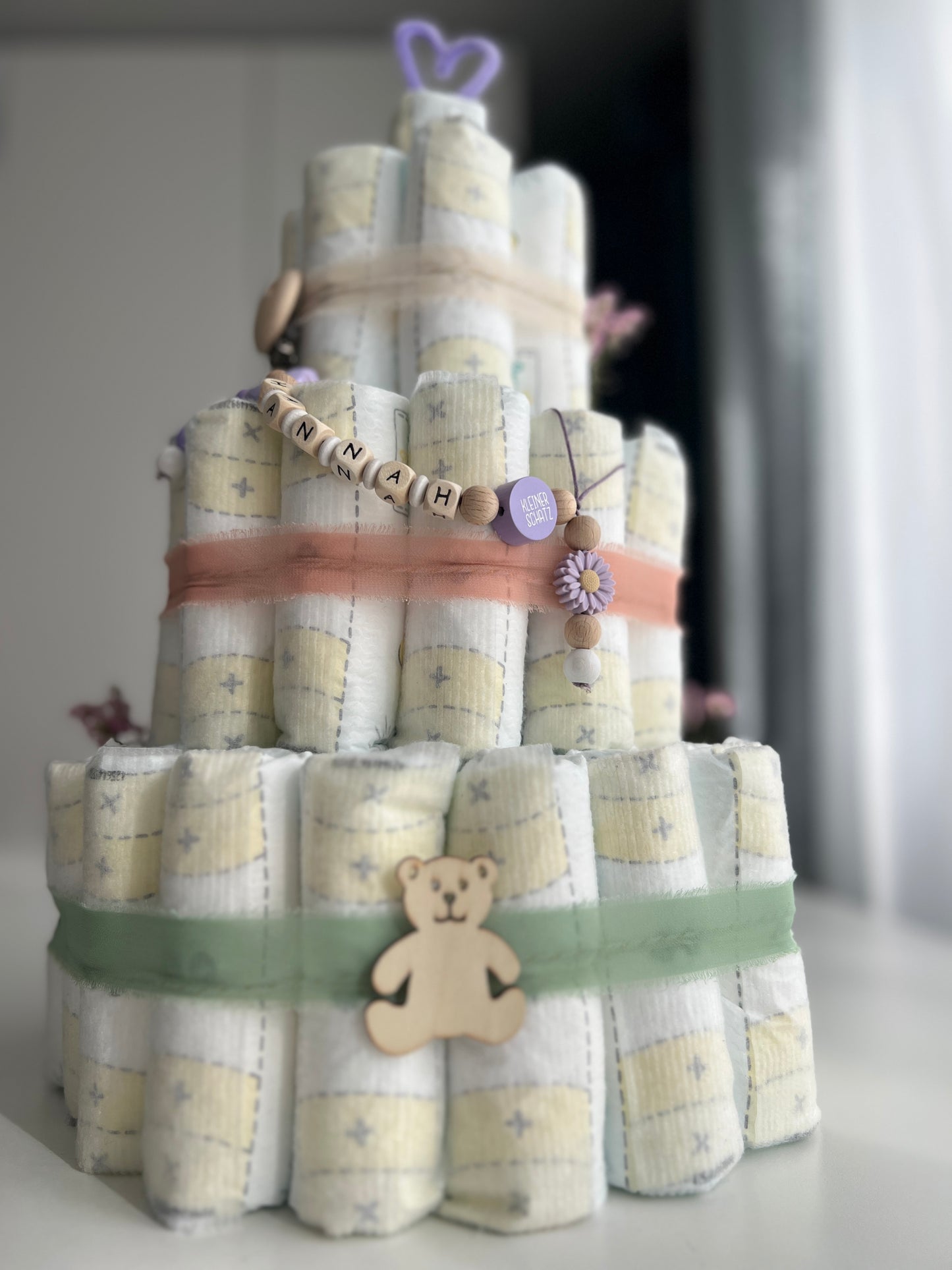Windeltorte mit Nuggikette und Greifling, liebevoll verpackt als Geschenk.
